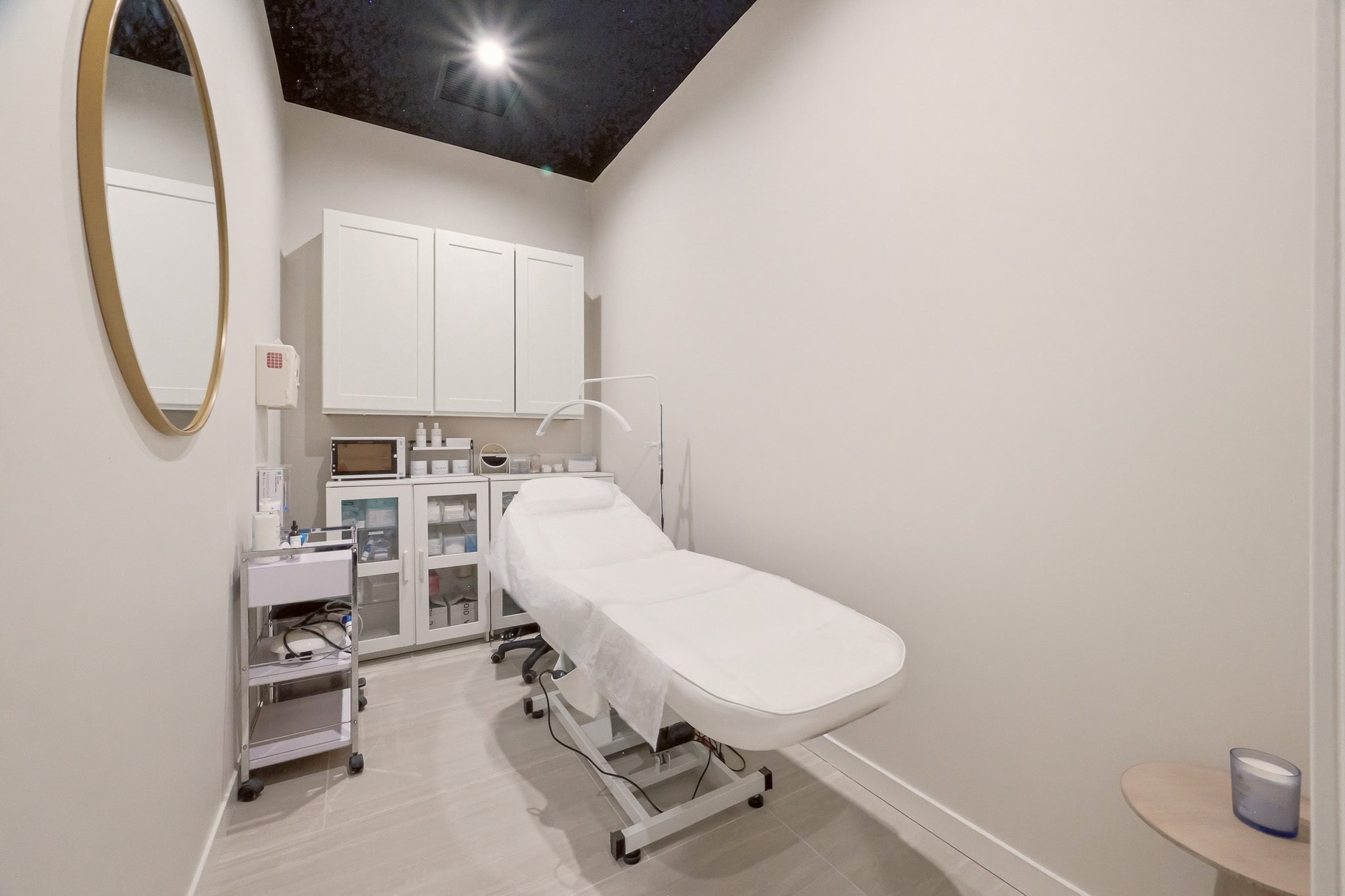 Private treatment room at Ovilla Medical & Wellness with a white treatment bed, round mirror and built-in cabinetry